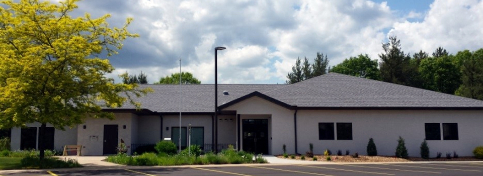 The library is one story with plantings and a bench near the entry. 